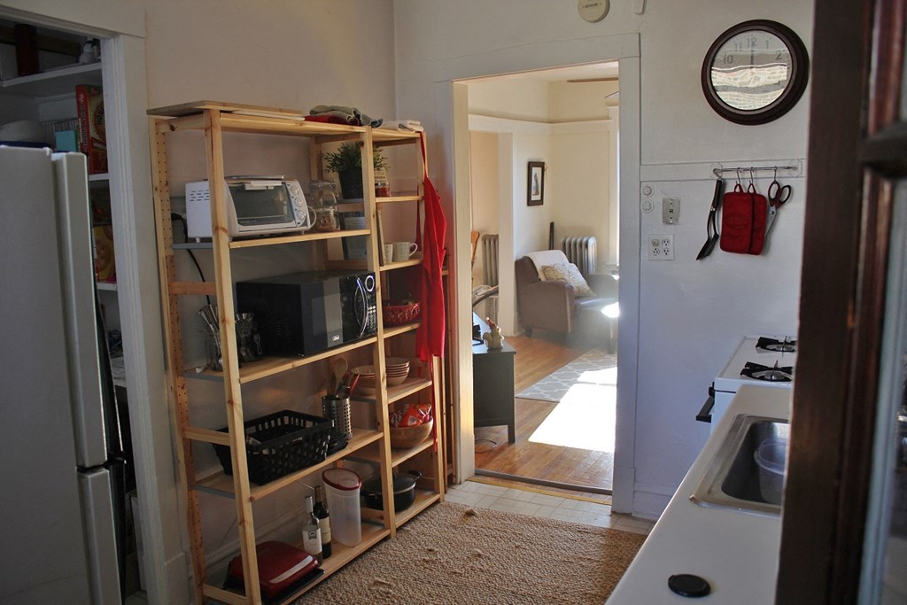 a kitchen with a shelf and a door to a living room