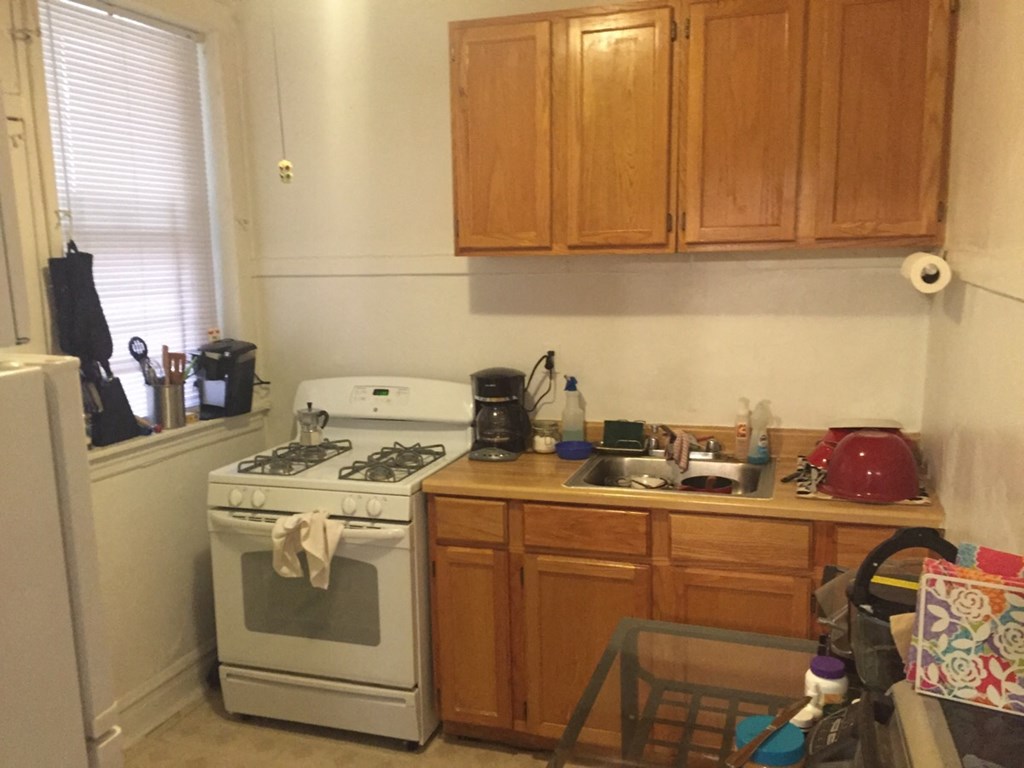 a kitchen with a stove and sink and wooden cabinets
