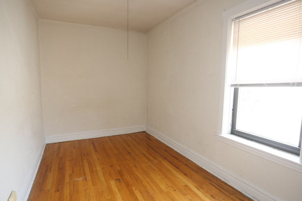 an empty room with wooden floors and two windows