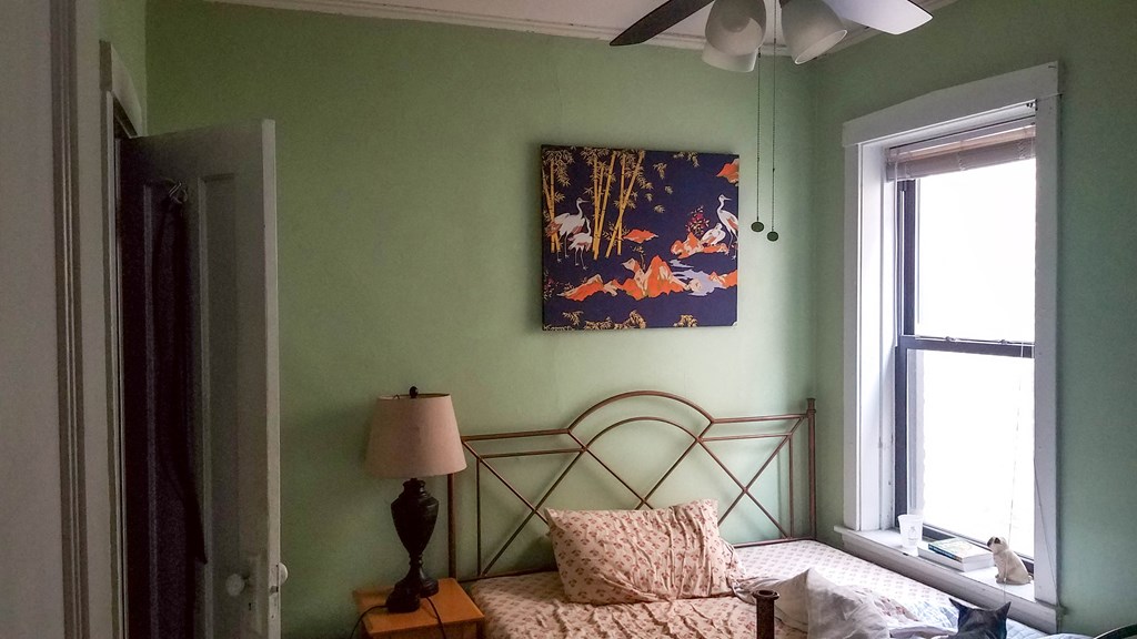 a bedroom with a bed and a painting on the wall