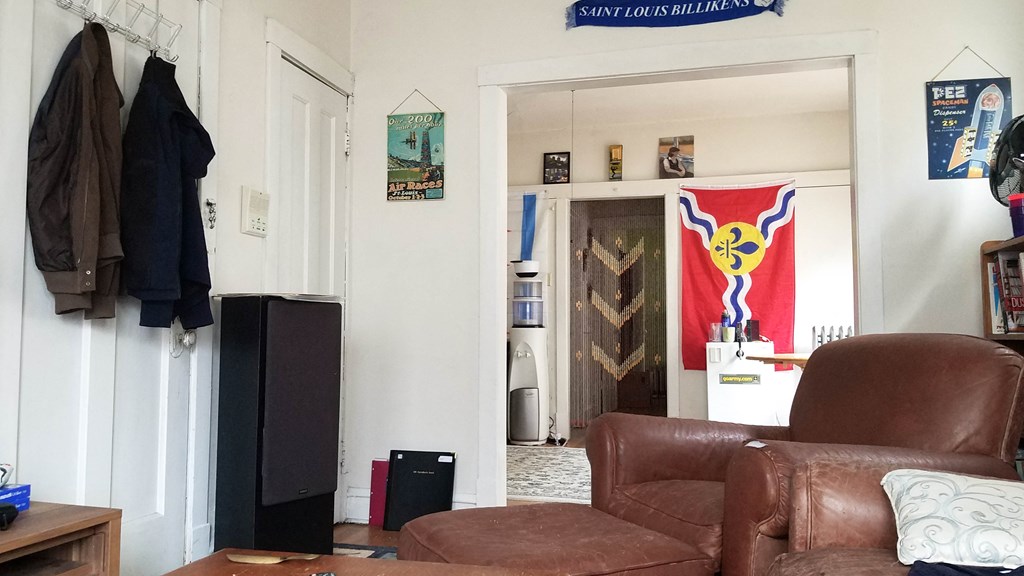 a living room with a brown leather chair and a doorway to a kitchen