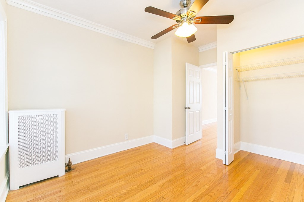 an empty living room with a ceiling fan and a door to a closet