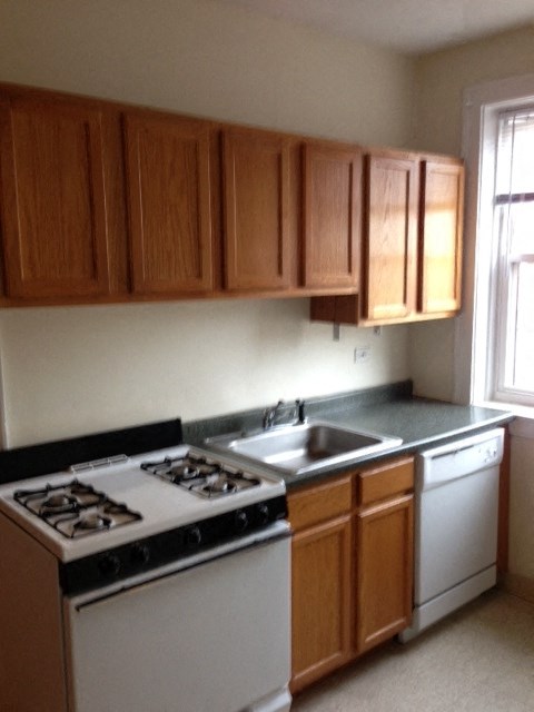 an empty kitchen with white appliances and wooden cabinets