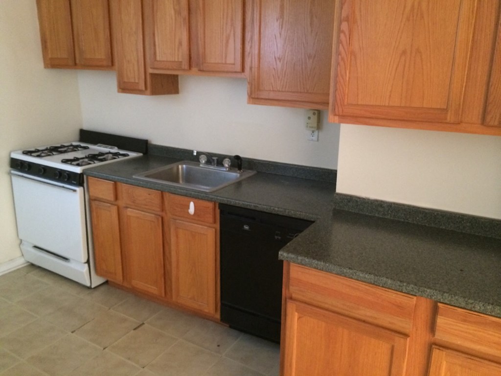a kitchen with wooden cabinets and a sink and a stove