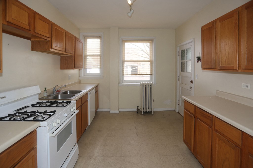 an empty kitchen with wooden cabinets and a white stove