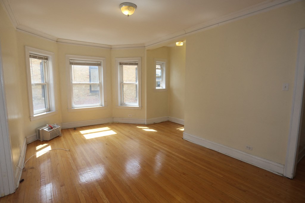 an empty living room with wooden floors and three windows