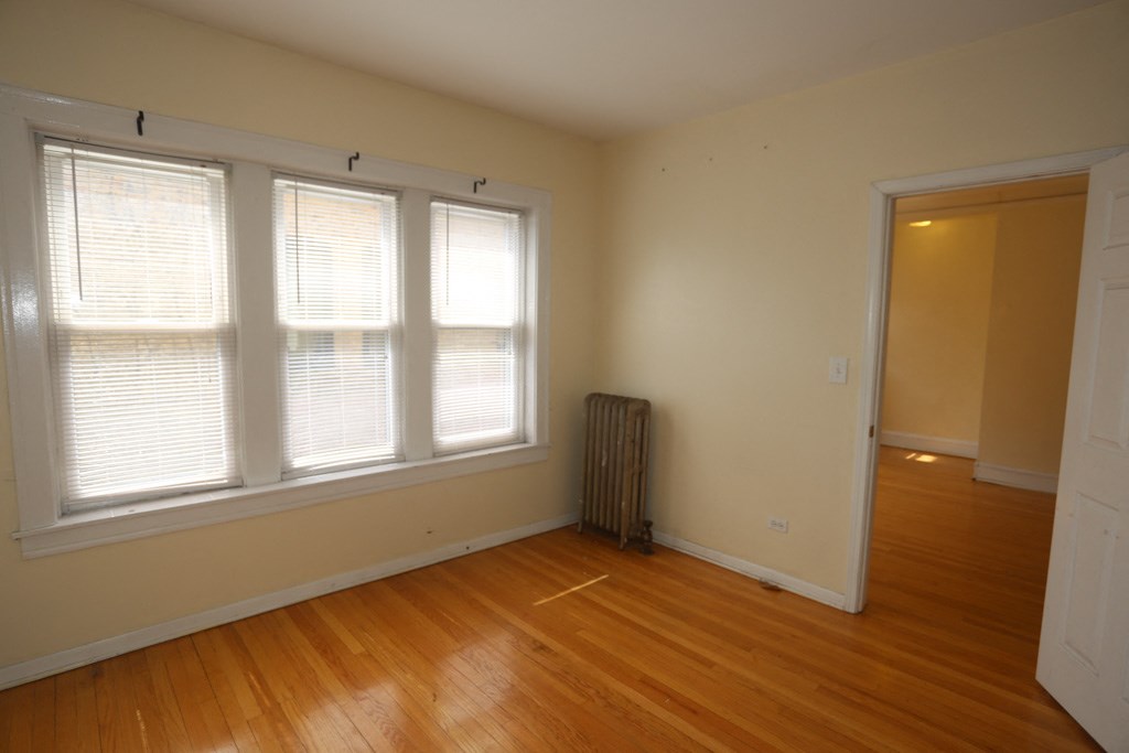 the living room of an empty house with a wood floor and three windows