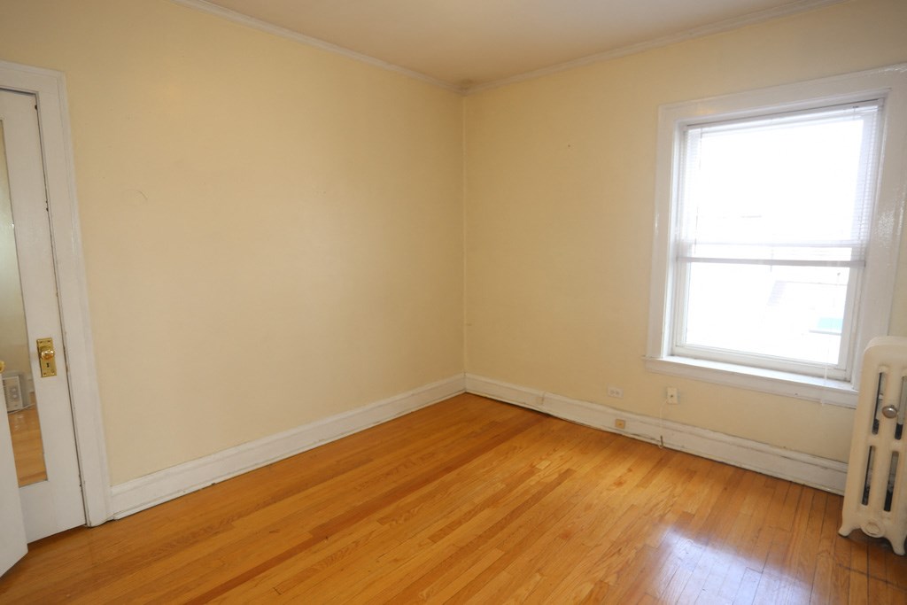 an empty room with wooden floors and two windows