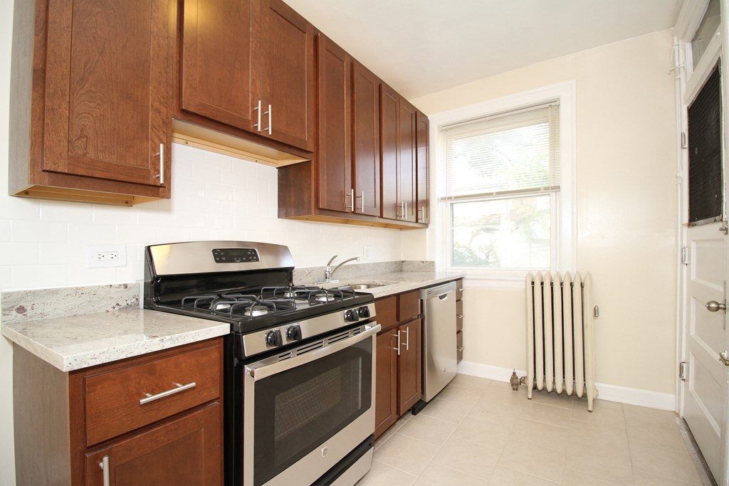 a kitchen with wooden cabinets and stainless steel appliances and a window