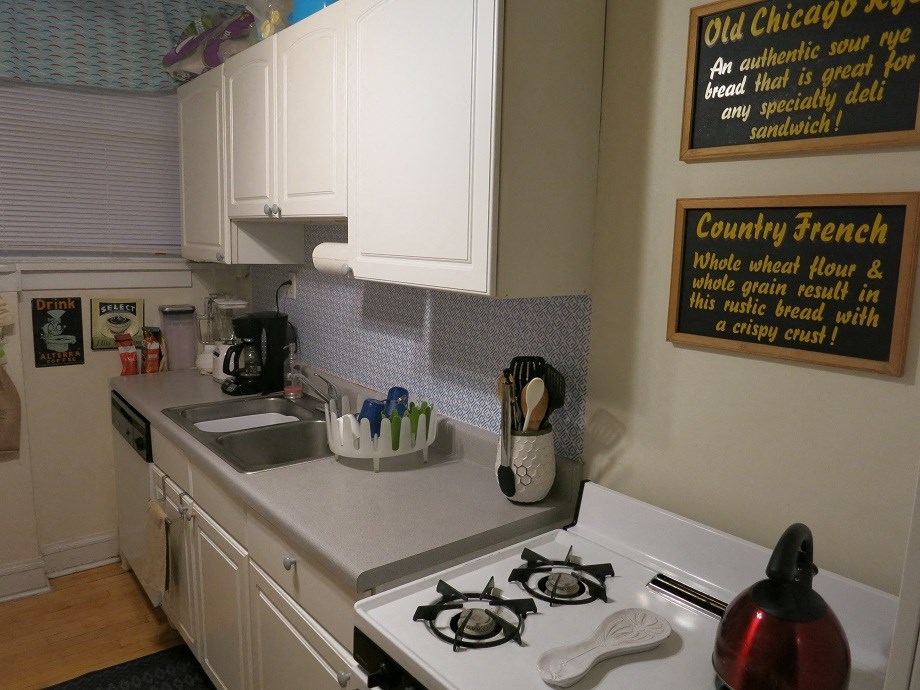 a small kitchen with a stove and sink and a sign on the wall