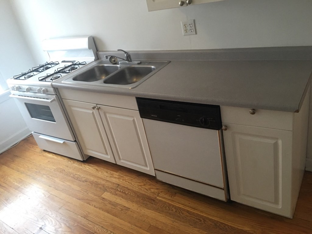 a kitchen with white cabinets and a sink and a stove