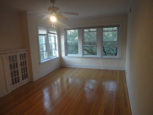 an empty living room with a wood floor and a ceiling fan