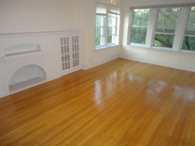 an empty living room with a wooden floor and a fireplace