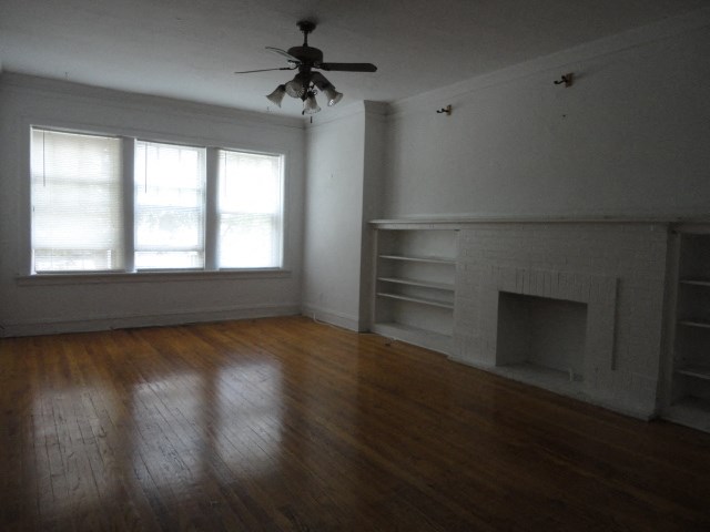 an empty living room with a fireplace and a ceiling fan