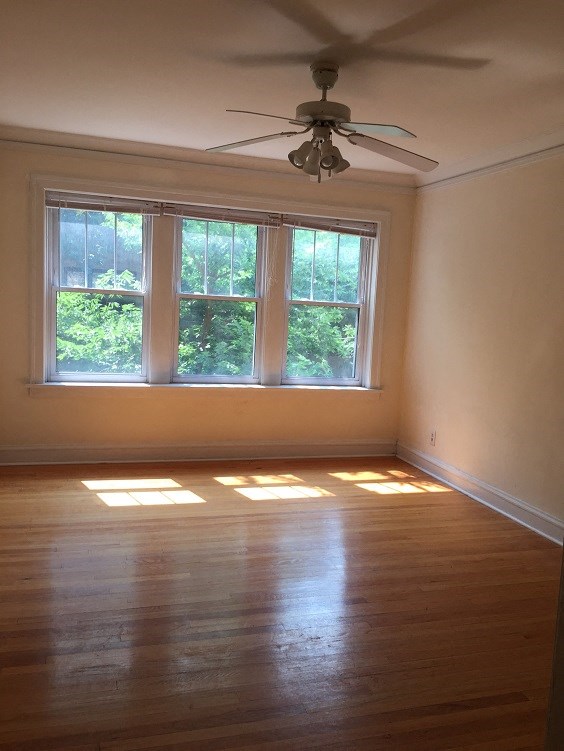 an empty living room with a ceiling fan and a window