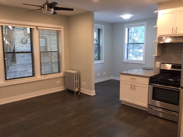 an empty kitchen with a stove and a ceiling fan