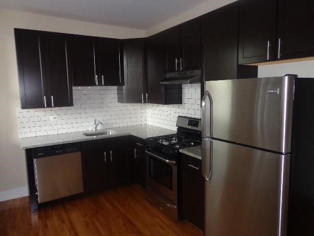 a kitchen with black cabinets and a stainless steel refrigerator
