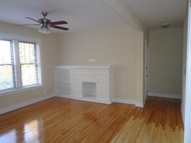 an empty living room with a fireplace and a ceiling fan