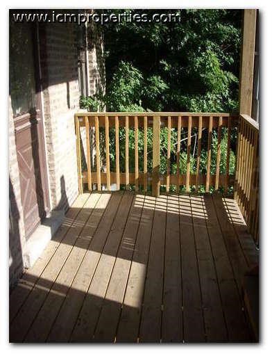 a porch with a wooden railing and some trees