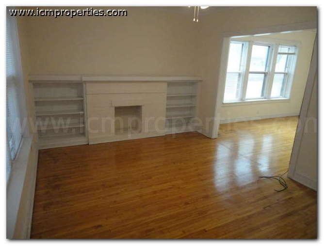 an empty living room with a wood floor and a fireplace