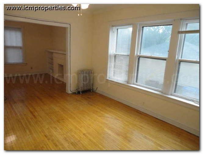 a living room with a wooden floor and three windows
