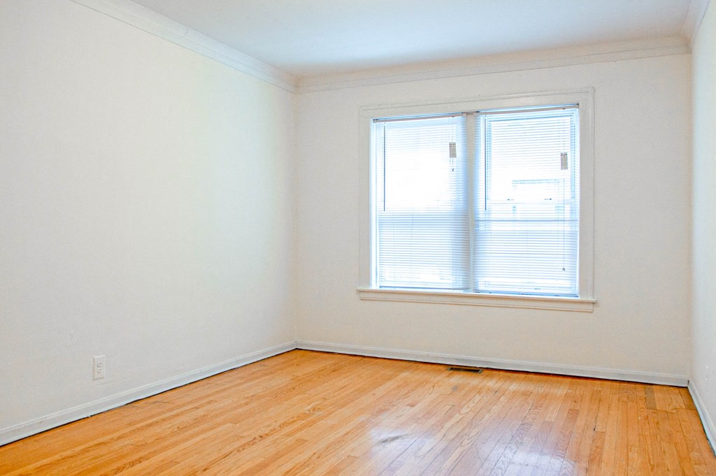 an empty room with a window and wooden floors
