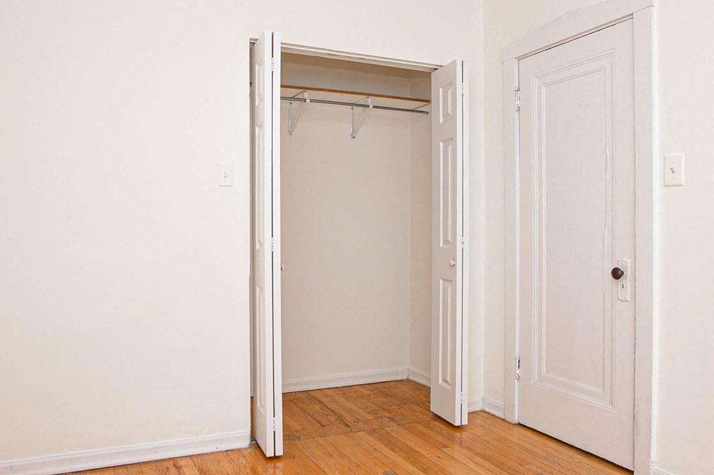 a bedroom with an open closet door and a wood floor