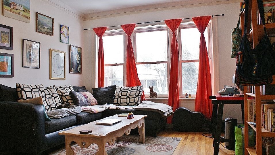 a living room with red curtains and a couch and a table