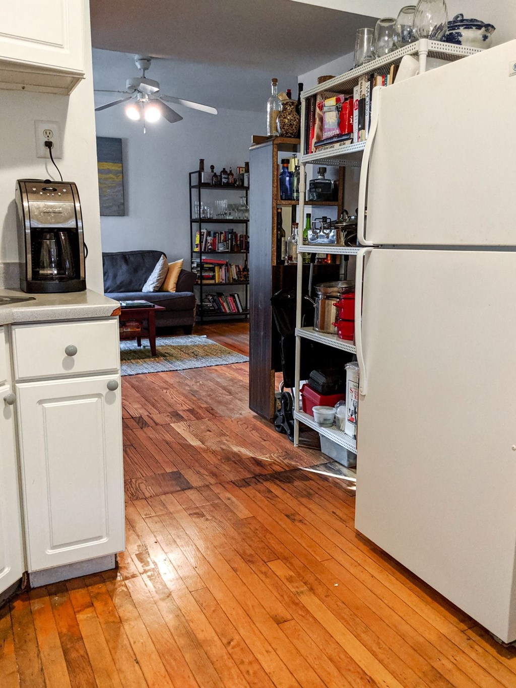 a kitchen with a refrigerator and a book shelf in the corner
