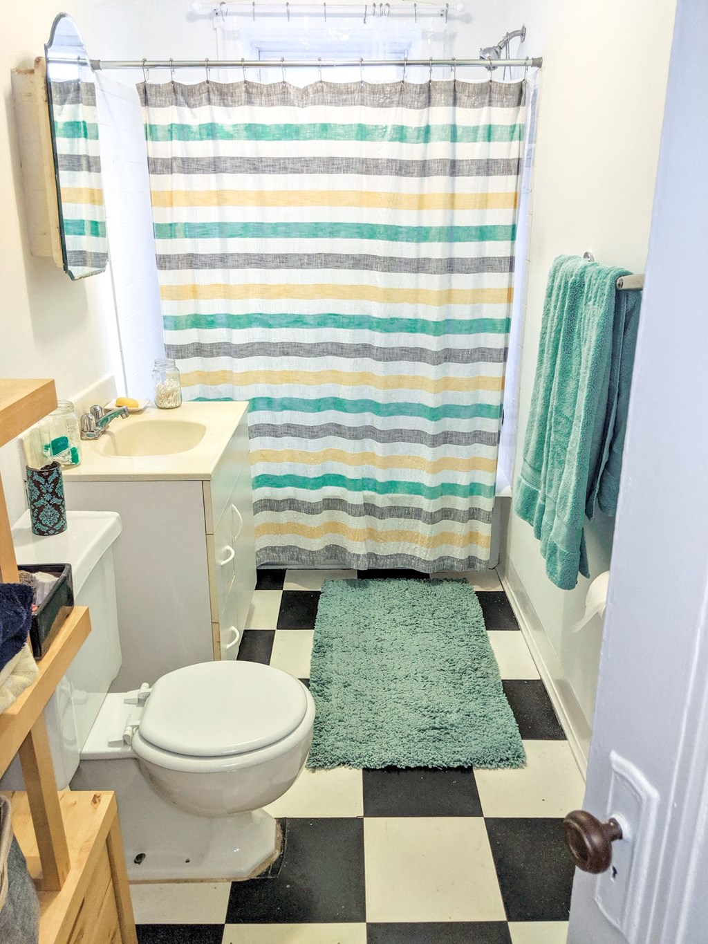a bathroom with a white toilet and a green rug
