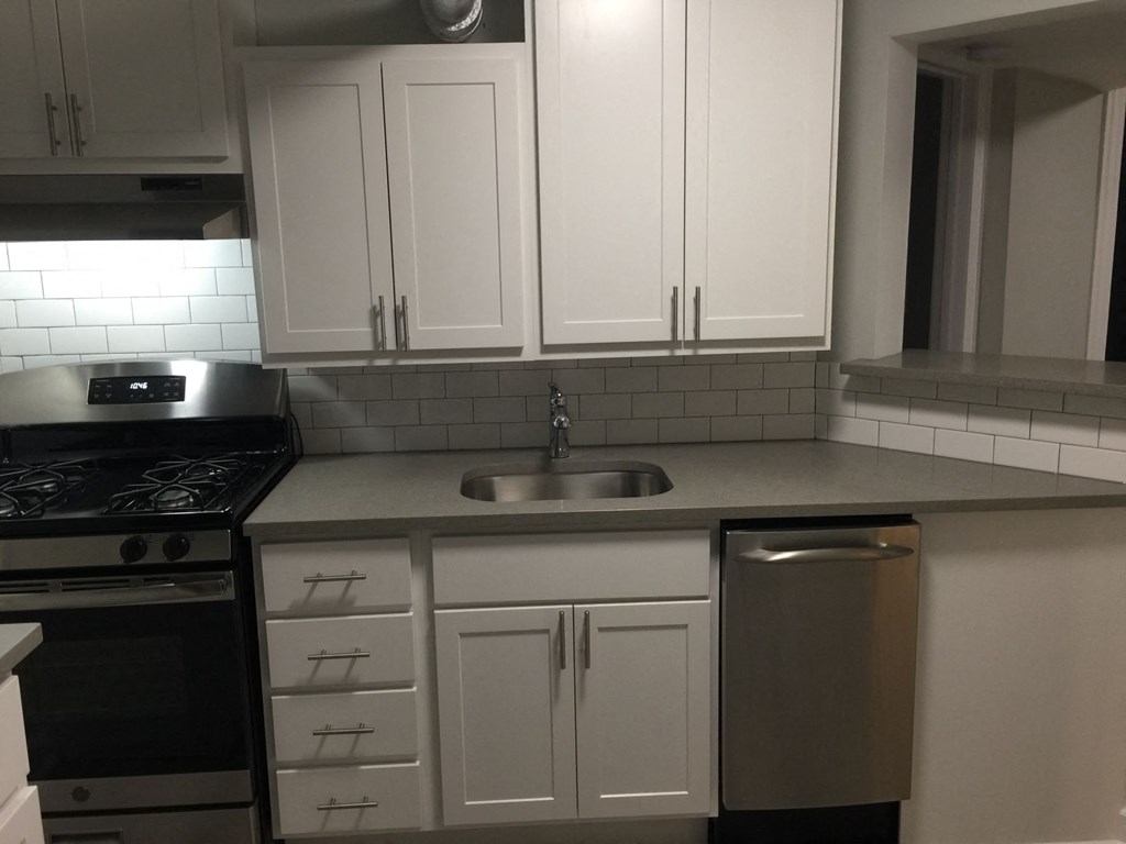 an empty kitchen with white cabinets and a sink