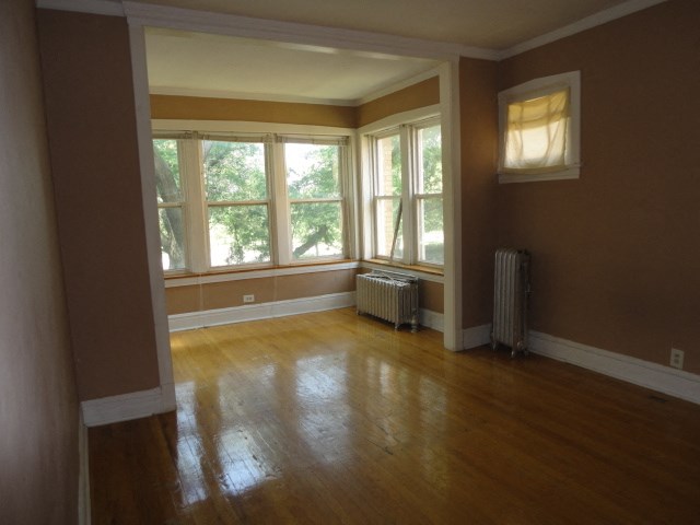 an empty living room with wooden floors and large windows