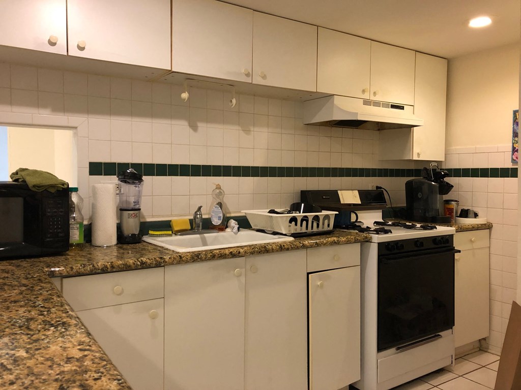 a kitchen with white cabinets and a sink and a stove