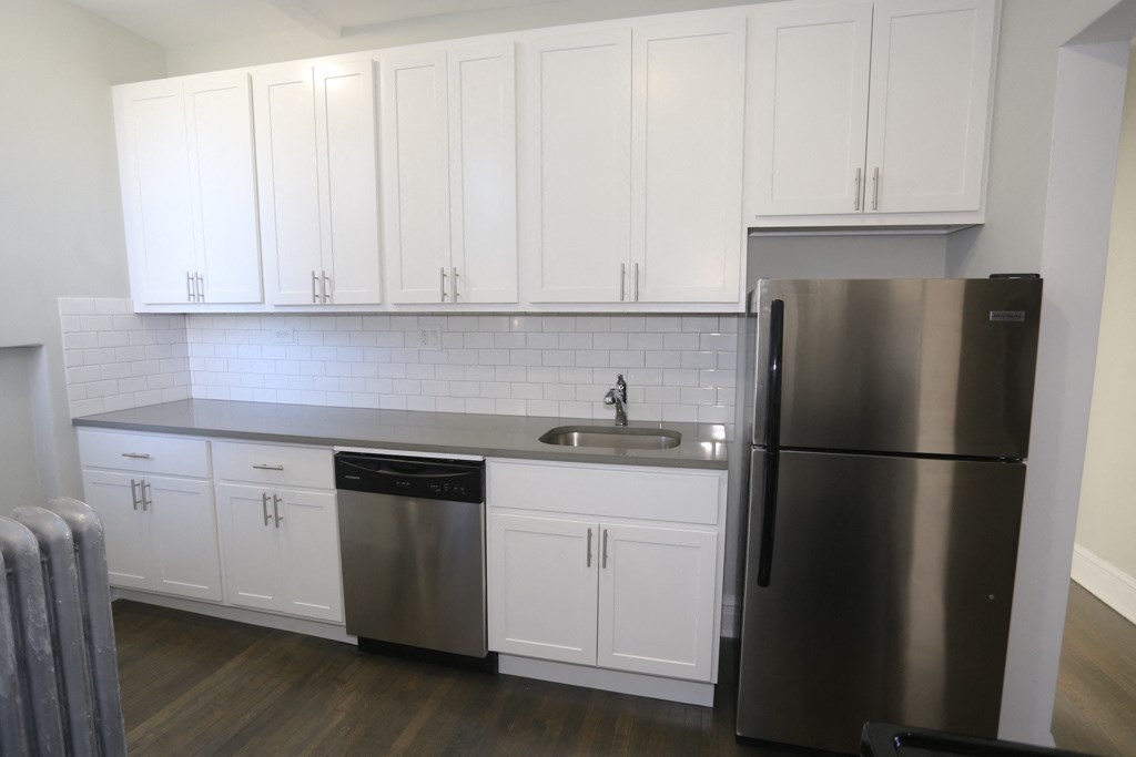 a kitchen with white cabinets and a stainless steel refrigerator