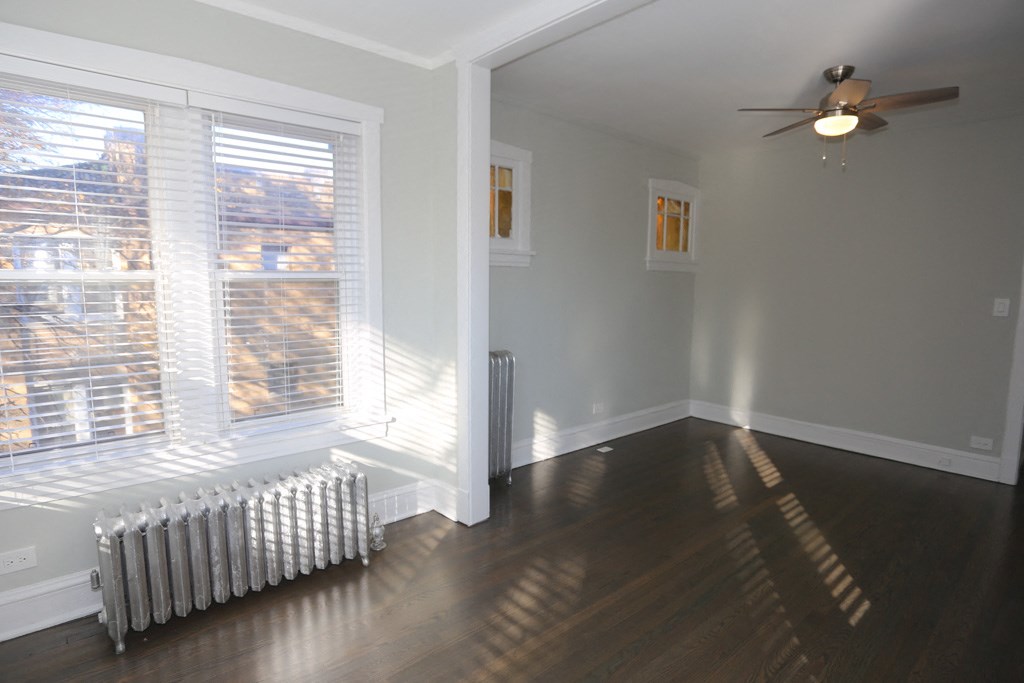 an empty living room with a radiator and a window