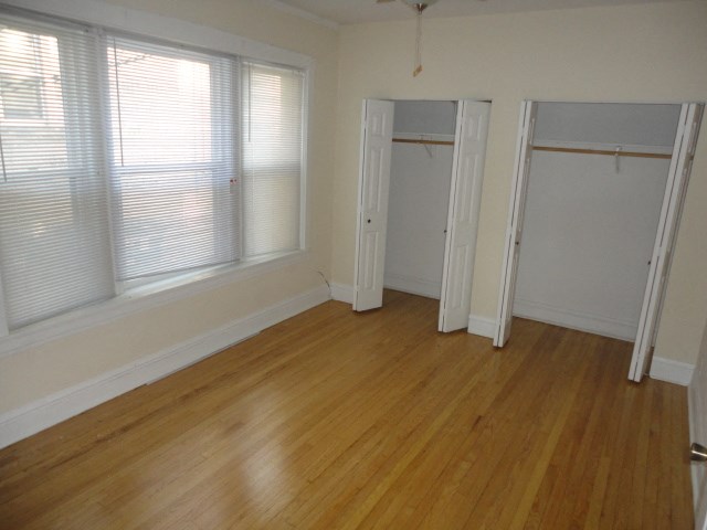 a bedroom with wood floors and white walls and a closet