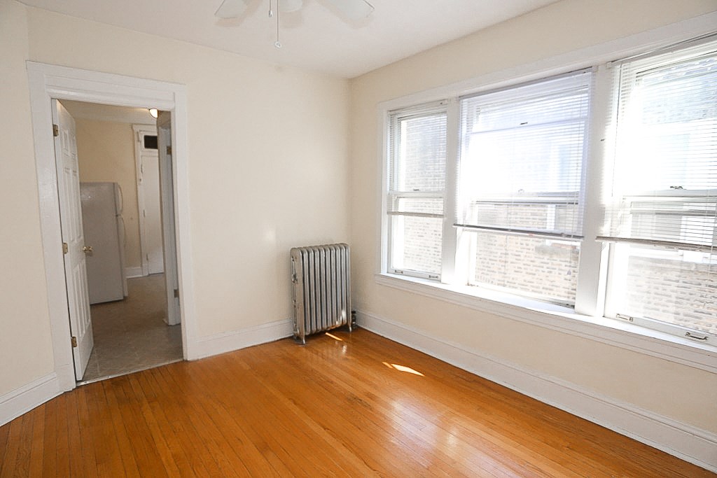 a room with a wood floor and a radiator and two windows