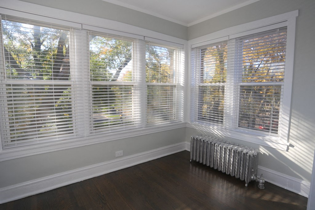 a large bay window with white blinds in a room with a radiator