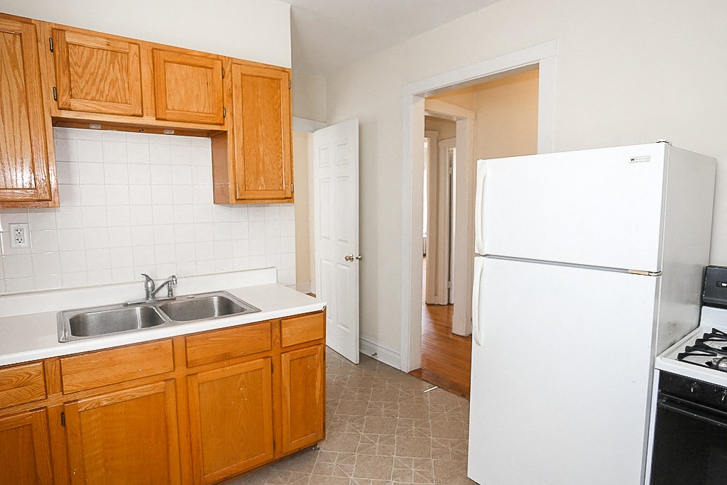 an empty kitchen with a white refrigerator and sink