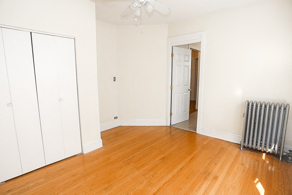 an empty living room with a radiator and a wood floor
