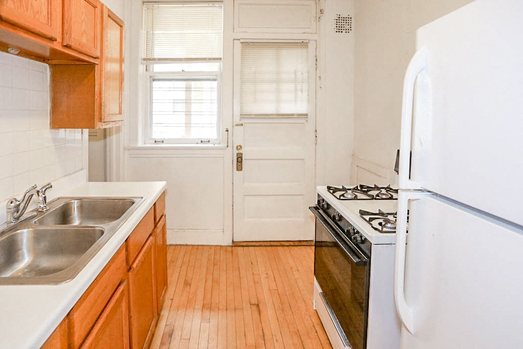 an empty kitchen with wooden floors and white appliances