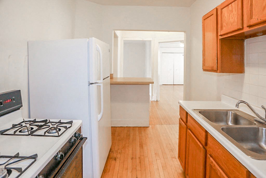 an empty kitchen with a stove and a refrigerator