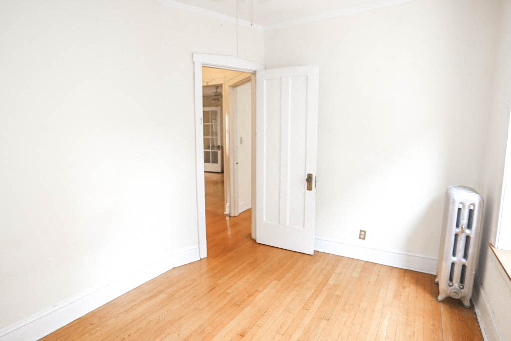 a room with a wooden floor and white walls and a white door