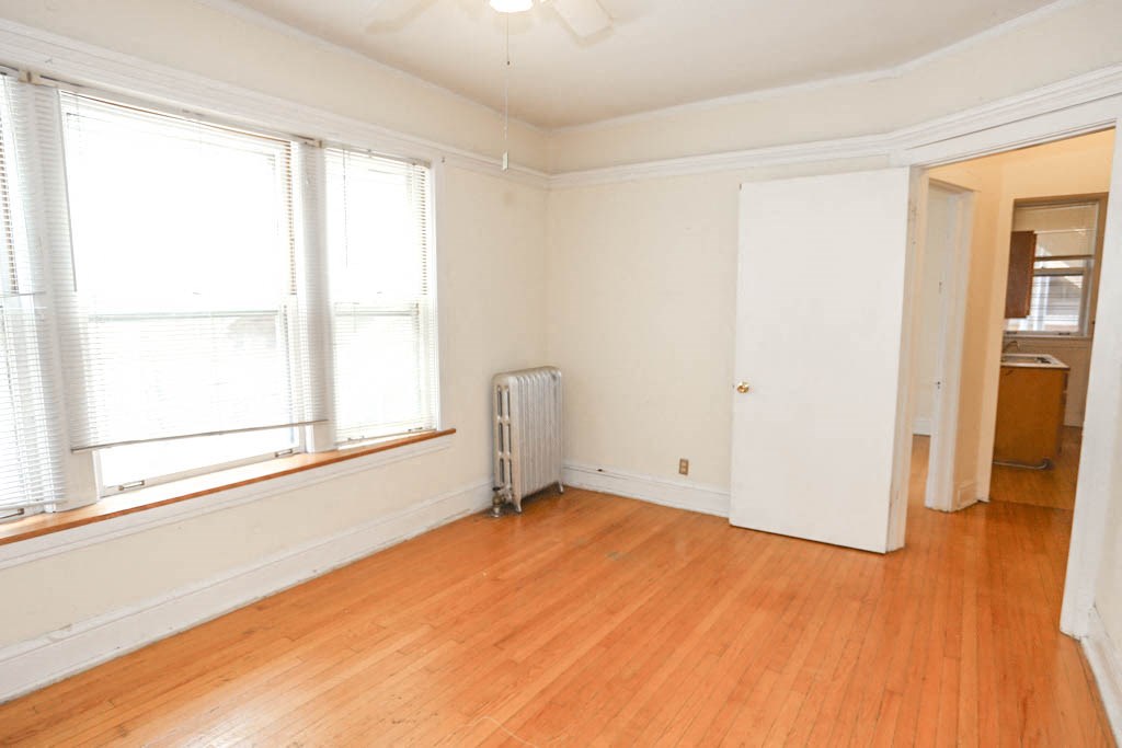 a room with a wood floor and a radiator and two windows