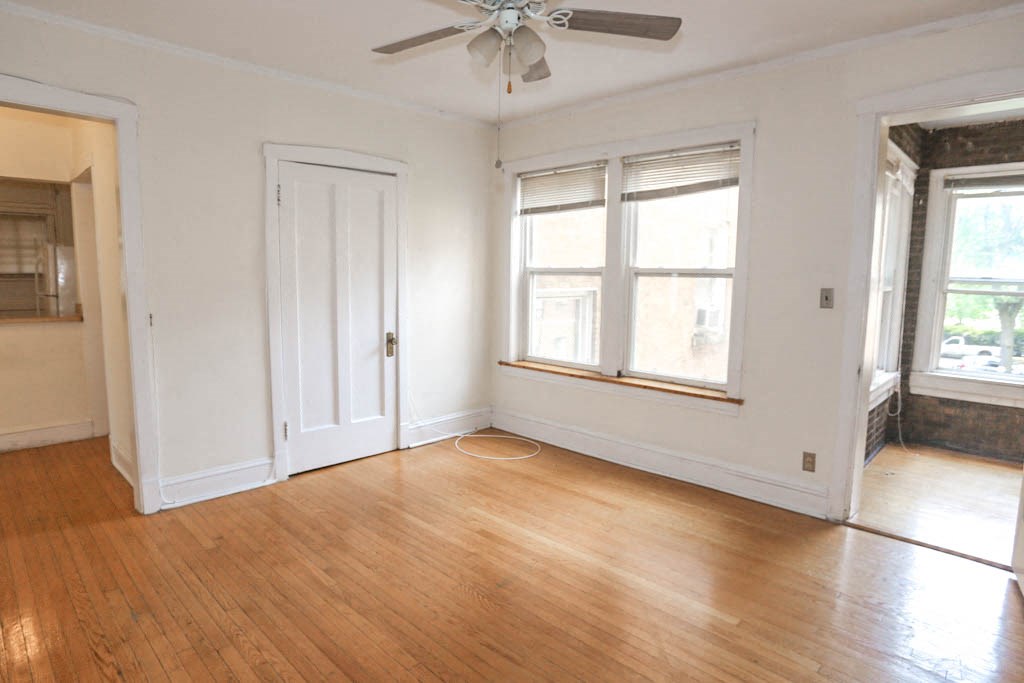 an empty living room with wood floors and a ceiling fan