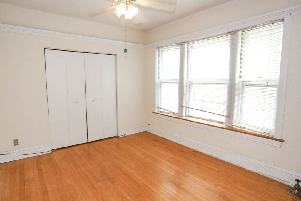 a bedroom with wood floors and a window and a closet