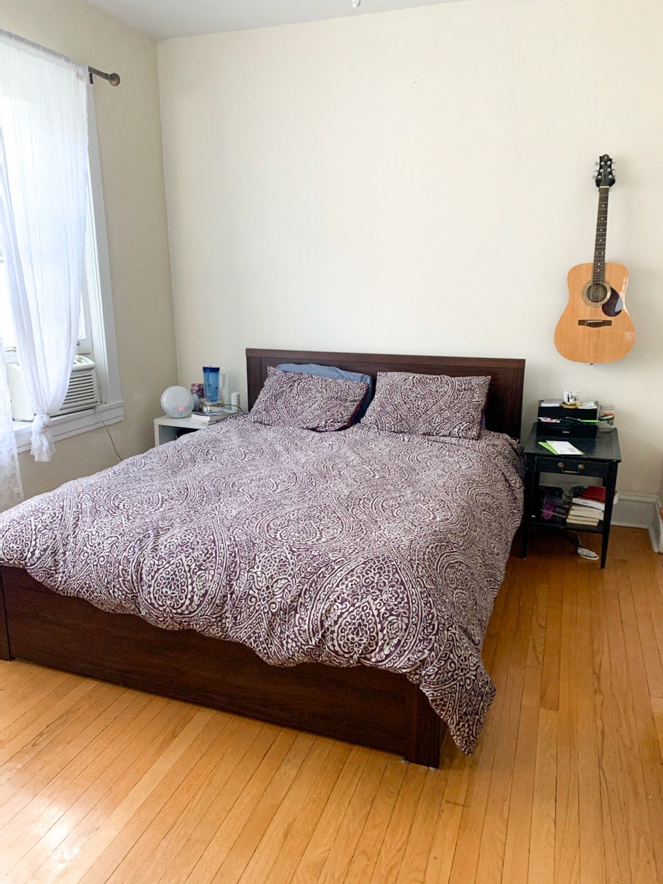 a bedroom with a bed and a guitar on the wall