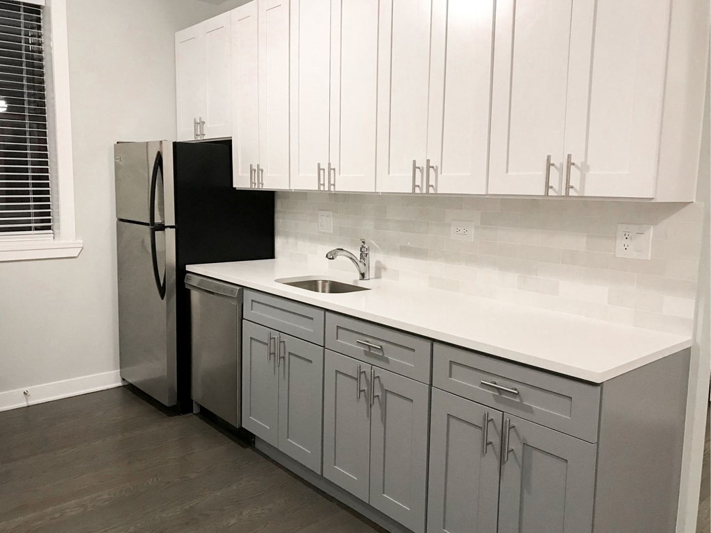 a white kitchen with white cabinets and a stainless steel refrigerator