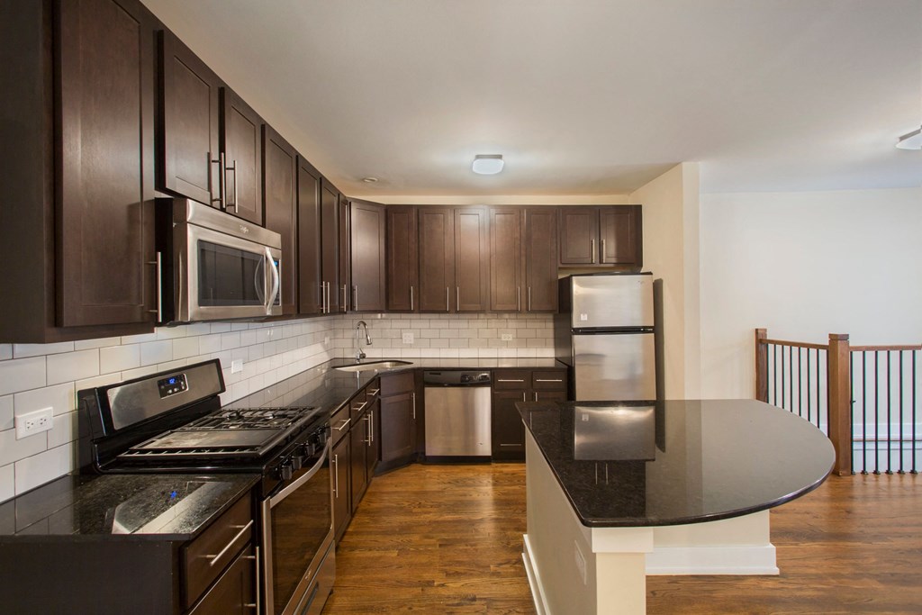a kitchen with dark wood cabinets and black counter tops and a black counter top island
