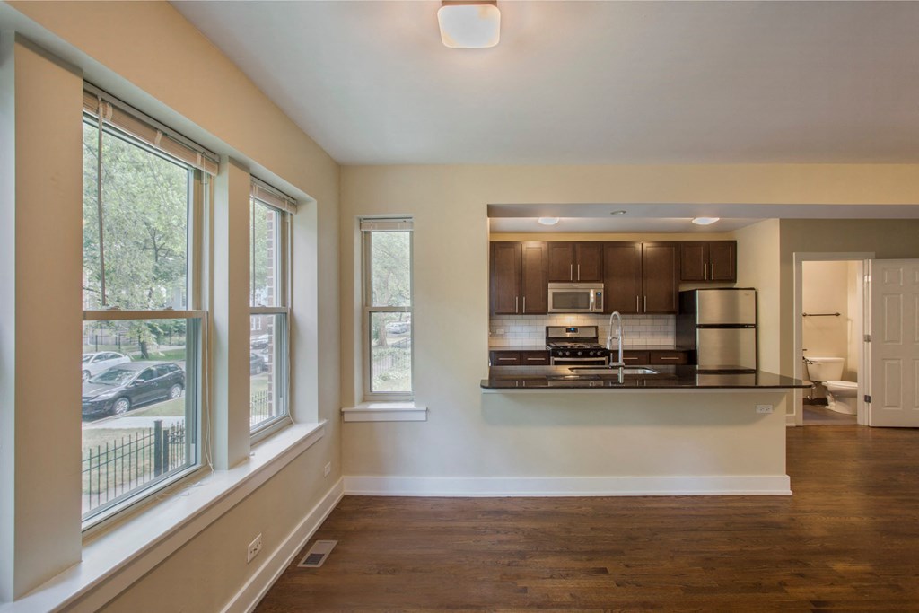 an empty living room with a kitchen and a large window